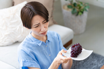 ブドウを食べる若い女性　ライフスタイルイメージ