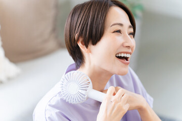 ハンドファンを使う若い女性　ライフスタイルイメージ