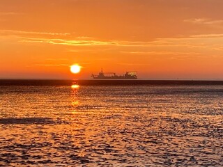 Sonnenaufgang am Meer in Cuxhaven an der Nordsee mit Schiff am Horizont