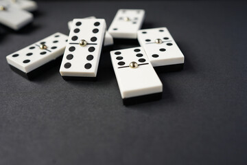 white domino blocks on black background. There are some benefits of playing domingo; helps to develop critical thinking skills, bond with families and social groups, reduces stress, improve memory.