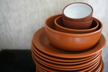 Stacked clay plates and bowls in the kitchen. The clay plate and bowl are ideal for dinnerware