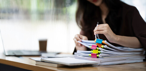 Businesswoman hands working in Stacks of paper files for searching and checking unfinished document...