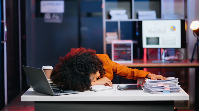 Business woman drinking coffee to get some energy for working overtime sitting at desk using computer and doing overtime project.