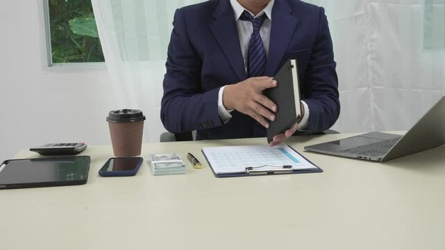 A banker in a suit works at a desk handling loans, analyzing client financial data, providing financial advice, dealing with stocks and the stock market, and studying economic situations.