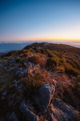 Naklejka premium Hiking on the highest peak of Madeira Pico Ruivo next to the cottage Abrigo do Pico Ruivo. Views of the surrounding mountains lanscape during sunrise