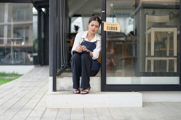 Asian female coffee shop owner Stressed barista Headache and regret hanging the shop closed sign on...