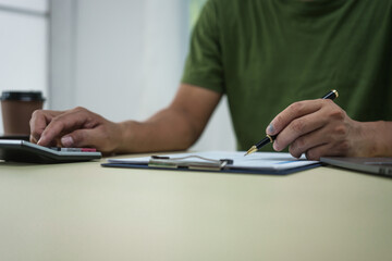 A householder manages household expenses while working at a desk, tracking various costs such as transportation, housing, groceries, dining, healthcare, utilities, and personal items to maintain