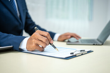 A banker in a suit works at a desk handling loans, analyzing client financial data, providing financial advice, dealing with stocks and the stock market, and studying economic situations.
