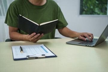 A householder manages household expenses while working at a desk, tracking various costs such as...