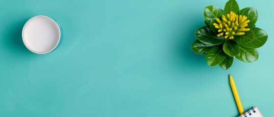 Obraz premium Top view of a turquoise desk with a coffee cup, notepad, yellow pencil, and a potted plant. Minimalist workspace background.