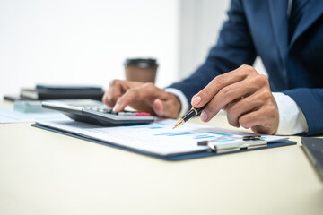 A banker in a suit works at a desk handling loans, analyzing client financial data, providing financial advice, dealing with stocks and the stock market, and studying economic situations.