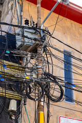 Chaotic power lines and cables crowding utility poles in Santa Marta, Colombia. Urban infrastructure overload in South American city.
