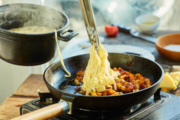 Step-by-step cooking process. Add the cooked homemade noodles to the pan with fried tomatoes, onions and sausage