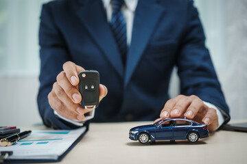 A man in a suit works at his desk selling cars and online car insurance with low interest rates, offering car loans, vehicle financing, and comprehensive vehicle coverage