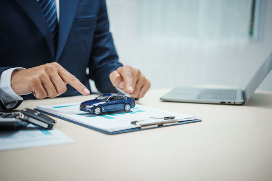 A man in a suit works at his desk selling cars and online car insurance with low interest rates, offering car loans, vehicle financing, and comprehensive vehicle coverage