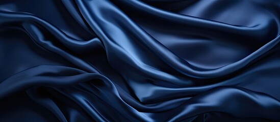 Fototapeta premium Luxurious dark blue silk satin background with soft folds, ideal for adding text or design with copy space image for a variety of occasions like birthdays or holidays.