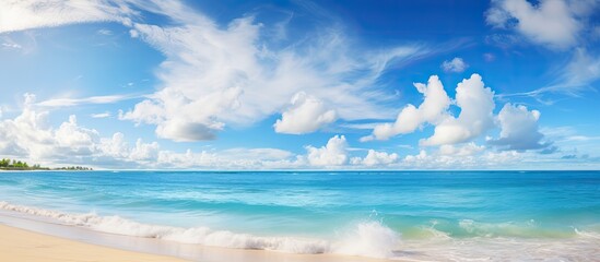 Fototapeta premium Scenic beach vista with vibrant sun over turquoise ocean and light clouds in blue sky, perfect for copy space image.