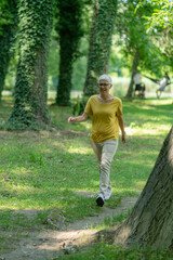 Senior woman enjoying a leisurely walk in the park for health and relaxation.