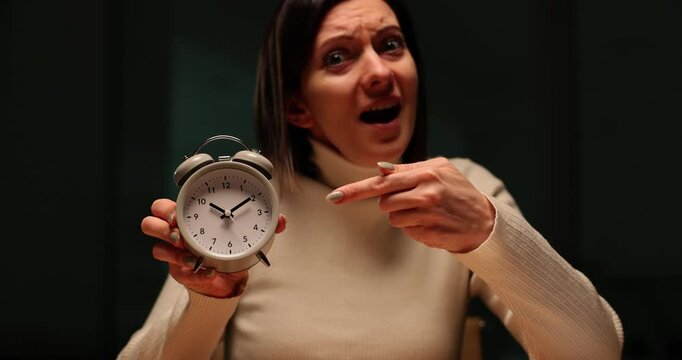 Woman points on alarm clock warning about deadline