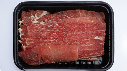 Sliced ​​beef in a black plastic container with a white background