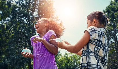 Children, energy and water balloon for friends in a park with splash fun, playing and bonding in...