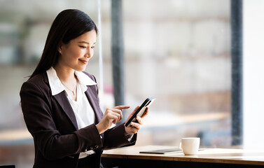 Beautiful asian businesswoman sit in the cafe, using smartphone and smiling. stock photo