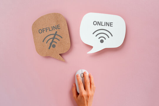Online offline text and symbol on real speech bubble paper cut with hand using computer mouse on pink background