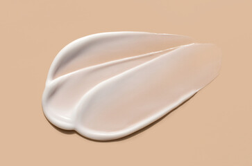 creamy smear of white cosmetic texture close up on beige background skin care concept