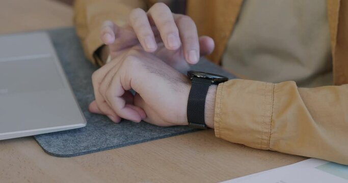 Close-up of male hand using smart watch touching gadget display enjoying electronic device at desk. Modern technology and people concept.