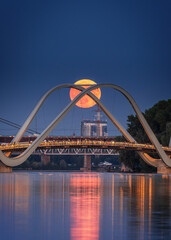 Pink strawberry Full Moon rises behind of the pedestrian bridge in Obolon district, Kyiv, Ukraine