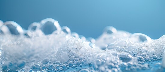 White soap bubbles foam on blue background. Suds shower texture macro view photo, shallow depth of field. Copy space image. Place for adding text and design