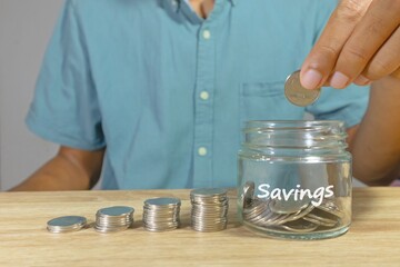 Man putting coins into a glass jar for a savings