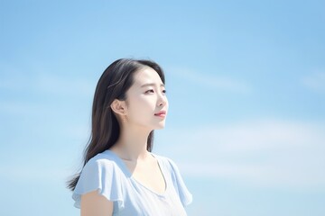 A woman in a blue shirt is looking up at the sky