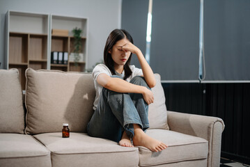 Obraz premium Asian woman sit Depression Dark haired pensive glance Standing by window and anxiety Copy space with a blanket on a sofa.