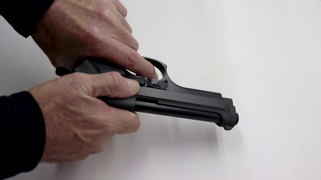 Person pushing a magazine with bullets into a firearm then cocks it 