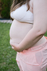 Obese young woman holds her belly. Outdoor exercises