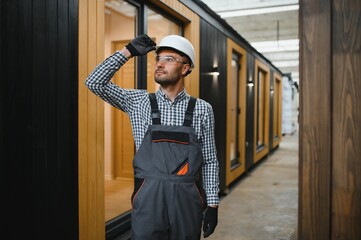 Portrait of a young carpenter worker in a helmet at the construction site of modular houses