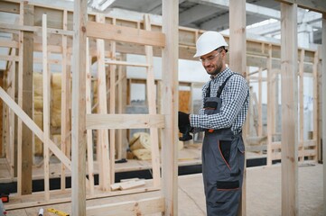 Portrait of a young carpenter worker in a helmet at the construction site of modular houses