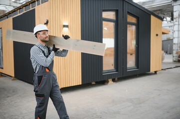 Process of construction new and modern modular house. Worker man in special protective uniform wear...