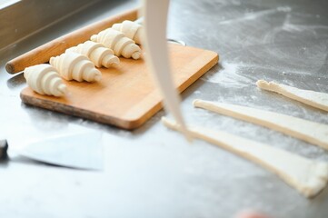 Producing classic croissants at the bakery shop. Woman is rolling dough into rolls for further...