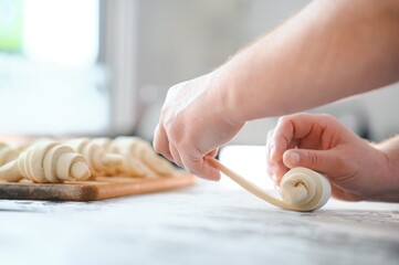 Producing classic croissants at the bakery shop. Woman is rolling dough into rolls for further...