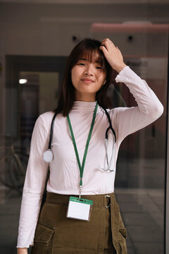 Smiling doctor with hand in hair standing in hospital