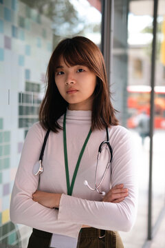 Doctor standing with arms crossed in front of glass near building