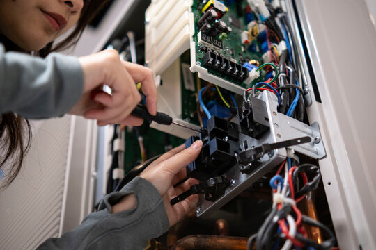 Hands of technician repairing air conditioner