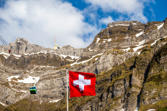 Swiss flag near Santis mountain under cloudy sky in Switzerland