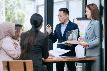 in corporate offices in Asia Business woman and man, they work together to plan a project. Analyze charts on laptop and discuss creative ideas with confidence and happiness.
