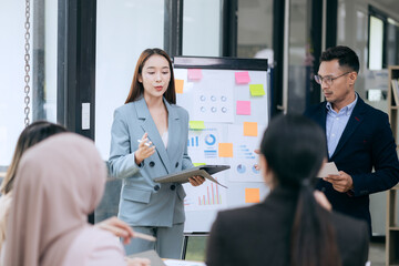 in corporate offices in Asia Business woman and man, they work together to plan a project. Analyze charts on laptop and discuss creative ideas with confidence and happiness.