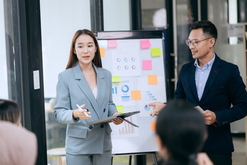 in corporate offices in Asia Business woman and man, they work together to plan a project. Analyze charts on laptop and discuss creative ideas with confidence and happiness.