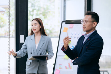 in corporate offices in Asia Business woman and man, they work together to plan a project. Analyze charts on laptop and discuss creative ideas with confidence and happiness.