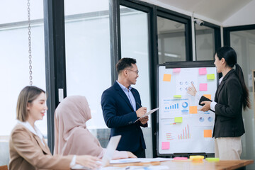 Professional business people taking part in a business meeting Discussing finances, strategies, and investing, they analyze charts on laptops. Demonstrate teamwork and effective communication.